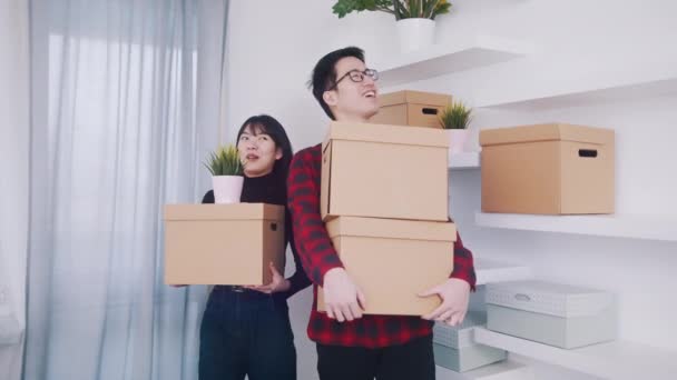 Junges asiatisches Paar zieht mit Pappkartons in neue Wohnung.  - Filmmaterial, Video