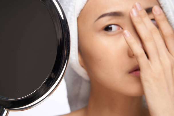 aziatische vrouw kijken naar de spiegel en aanraken met mijn hand gezicht schoon huid gezondheid cosmetologie - Foto, afbeelding