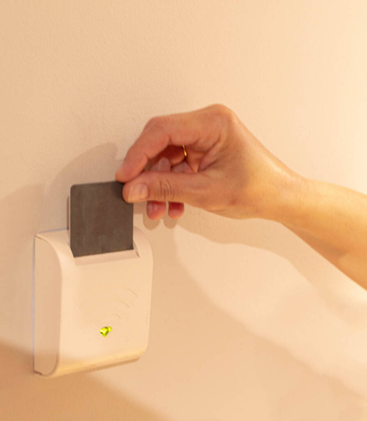 selektywne ustawianie ostrości jedną ręką poprzez włożenie karty hotelowej do urządzenia elektronicznego, aby włączyć światło w całym pokoju - Zdjęcie, obraz