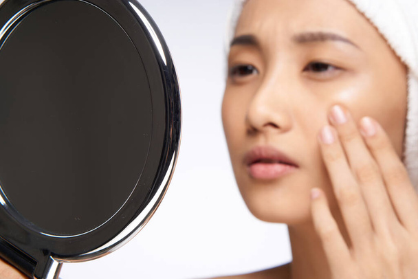 Mujer asiática mirando al espejo y tocando con mi mano la cara limpia la salud de la piel cosmetología - Foto, imagen