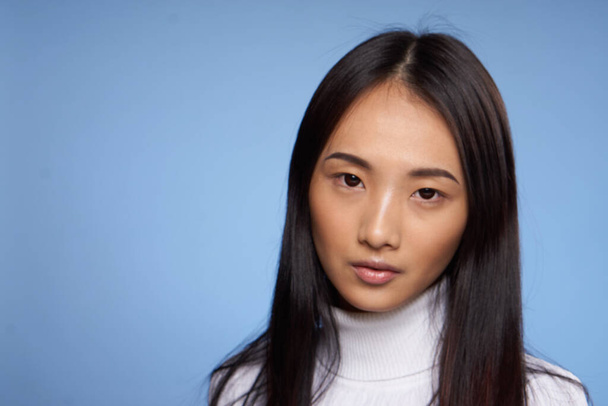 woman asian appearance white jumper blue background close-up model - Zdjęcie, obraz