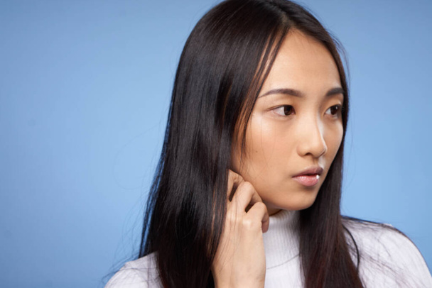pretty woman asian cosmetology white sweater blue background dark hair - Fotografie, Obrázek