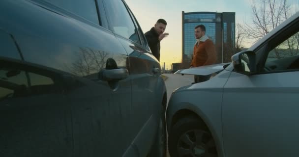 Duas pessoas discutindo e inspecionando os danos após o acidente de carro - Filmagem, Vídeo