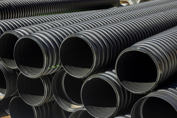 Tubos de PVC tubos de plástico apilados en filas en un sitio de construcción en la reconstrucción del sistema de drenaje de la ciudad - Foto, imagen