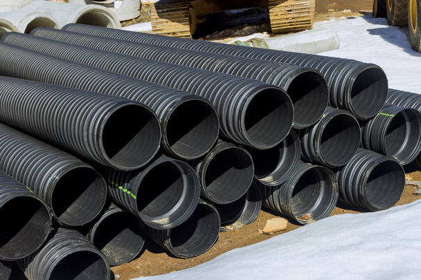 Tubi in PVC di plastica impilati in file in cantiere sulla ricostruzione del sistema di drenaggio della città - Foto, immagini
