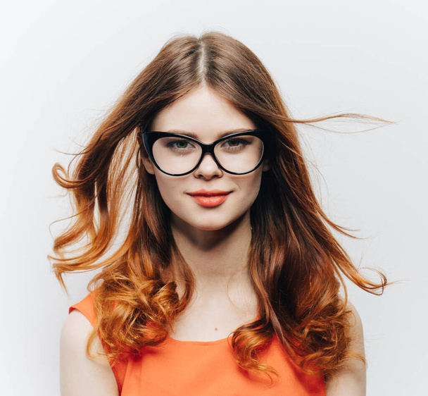 attraktive Frau mit lockerem Haar und Brille und orangefarbener Kleidung - Foto, Bild