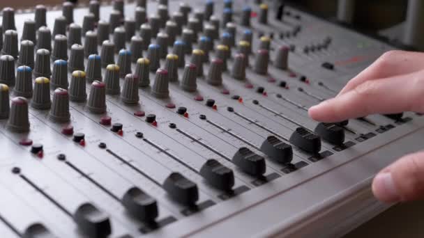 Sound Engineer, DJ beweegt schuifregelaars met vingers op audio mixer in de opnamestudio - Video