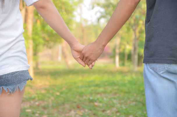 Пара тримає руки, що йдуть і розслабляються в саду
 - Фото, зображення