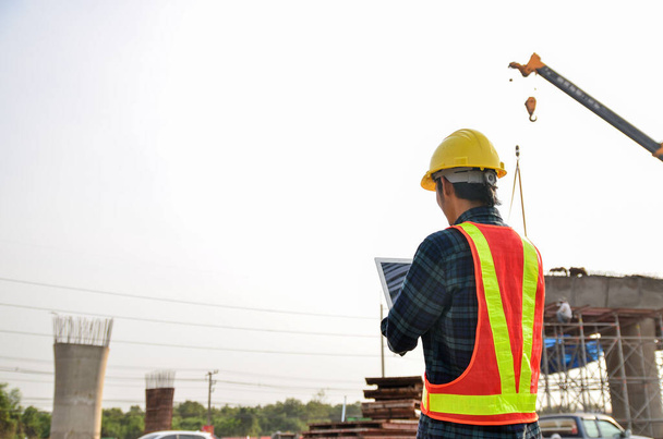 Ingenieros de construcción están utilizando tabletas para inspeccionar proyectos de construcción en el fondo de la obra. - Foto, Imagen