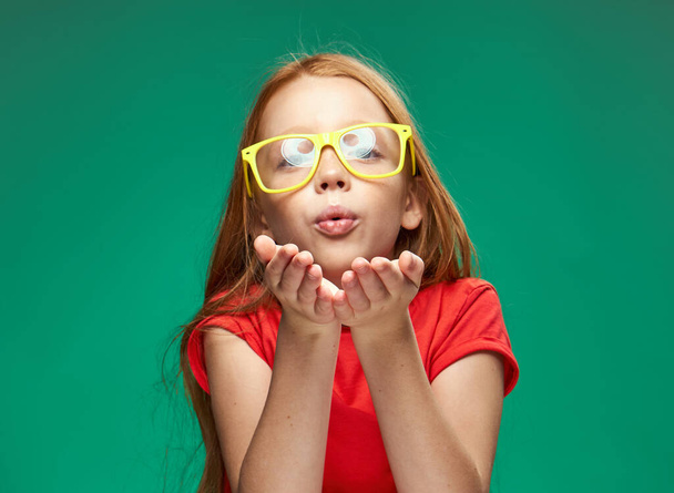 Девушка с рыжими волосами в желтых очках создает эмоции обрезанный вид на студию школы - Фото, изображение