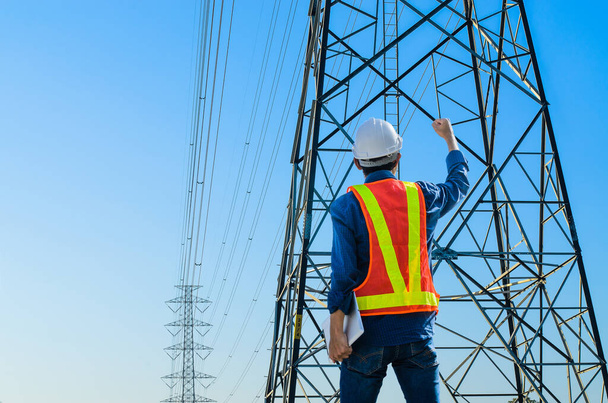 Successful engineers stand against electric poles on a blue background. - Photo, Image