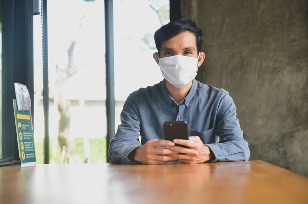 Biznesmen nosić maskę twarzy siedzi w kawiarni styl życia nowy normalny dystans społeczny po zamknięciu wirusa korony - Zdjęcie, obraz