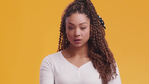 Zwijg. Studio portret van jong Afrikaans amerikaans tonen geheim gebaar, met de vinger op de lippen, oranje achtergrond - Video