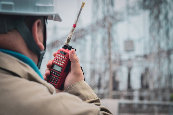 Egy rádió (walkie-talkie) kommunikálni a kezében egy férfi mérnök a munkahelyen. - Fotó, kép