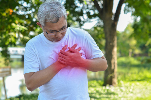 Un homme âgé souffre de douleurs cardiaques pendant l'exercice dans le parc. - Photo, image