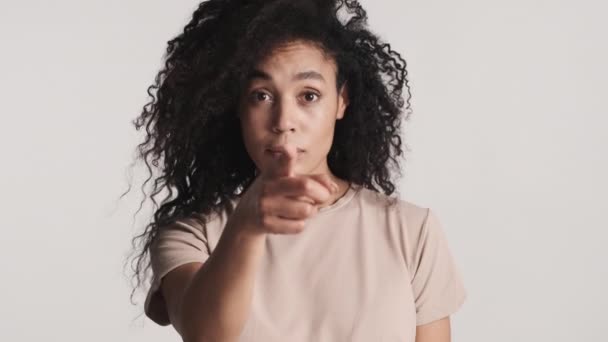 Attraente donna afro-americana indicano direttamente alla fotocamera con indice che ti sceglie su sfondo bianco - Filmati, video