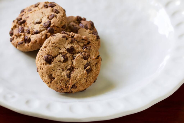 Un primo piano di alcuni deliziosi biscotti al cioccolato fatti in casa su un piatto di ceramica bianca. - Foto, immagini