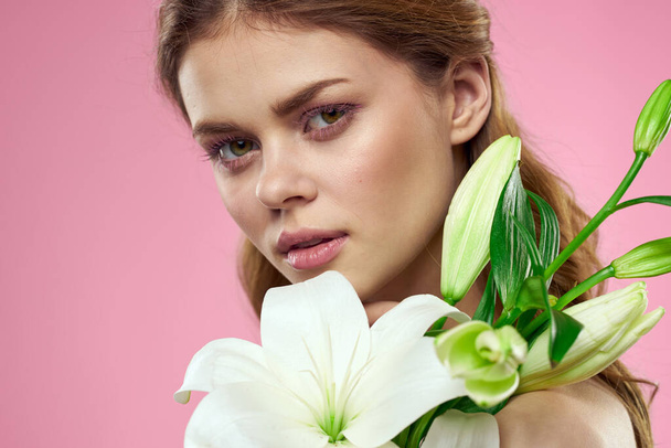Portrait of a beautiful woman with white flowers in her hands on a pink background Copy Space cropped view - Photo, Image