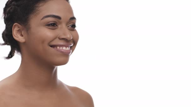 Stúdió portré afro-amerikai nő sima bőr mosolygós és félrenéz, fehér háttér, szabad tér - Felvétel, videó