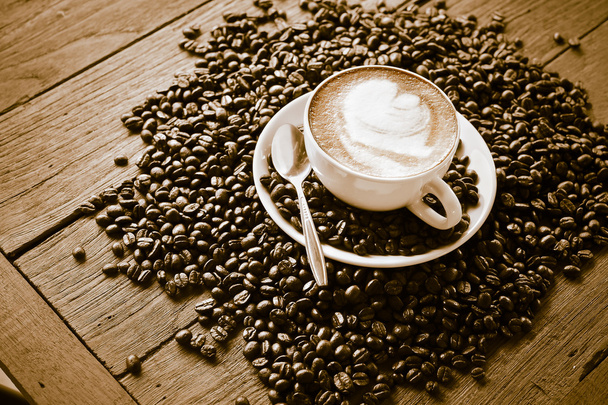 šálek kávy a kávových zrn na dřevěný stůl - Fotografie, Obrázek
