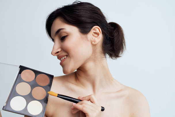 Mujer bonita con hombros desnudos aplicando maquillaje en la cara estilo de vida - Foto, Imagen
