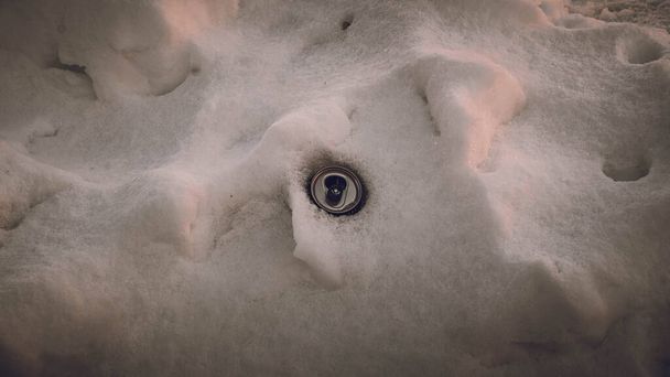 雪の中にアルミ製の空の瓶が隠されている。環境. - 写真・画像