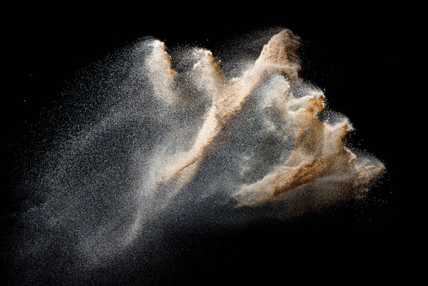 Sand flying explosion isolated on black background. Freeze motion of sandy dust splash. - Photo, Image