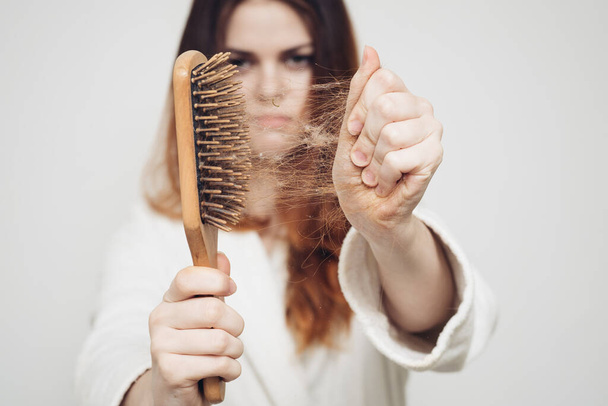 γυναίκα αφαιρεί μπούκλες των μαλλιών από μια χτένα απώλεια του μοντέλου προβλήματα υγείας - Φωτογραφία, εικόνα