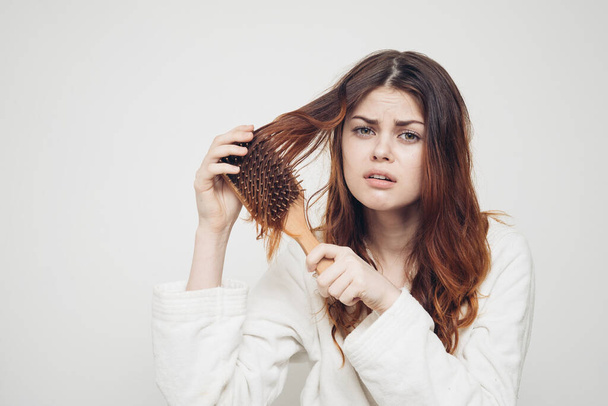 rudowłosa kobieta czesająca splątane loki na jasnym tle - Zdjęcie, obraz