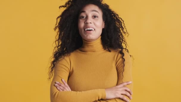 Genç, güzel, Afro-Amerikan bir kadın sarı arka planda kameraya bakıp mutlu bir şekilde gülüyor. Pozitif duygular - Video, Çekim