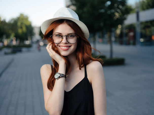 帽子と眼鏡をかけて通りを歩く魅力的な女性 - 写真・画像