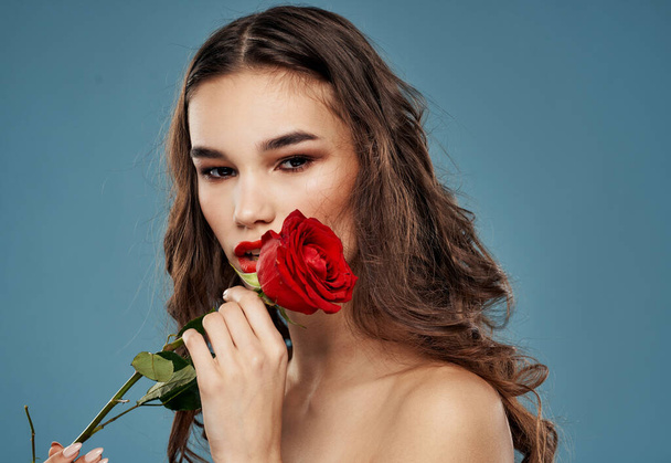 Γυναίκα με ένα τριαντάφυλλο στα δόντια της βράδυ μακιγιάζ μπλε φόντο μοντέλο - Φωτογραφία, εικόνα