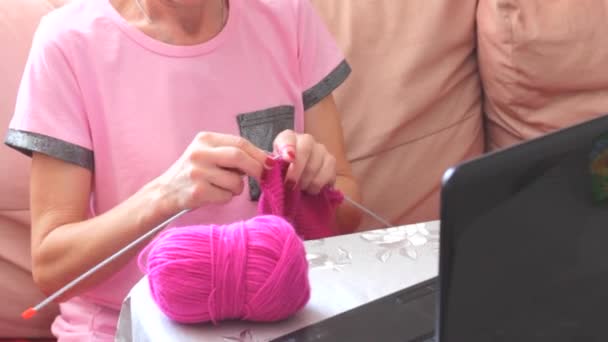 Oude volwassen vrouw met naalden breien gebreide sjaal ontspannen op de bank. Senior volwassen dame ouderling oma vrouwelijke handen doen handwerk hobby concept zitten op de bank thuis - Video