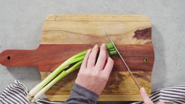 Biologische groene uien snijden op een houtsnijplank. - Video