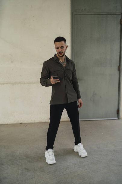 A Caucasian young man in casual style clothes holding a phone - Photo, image