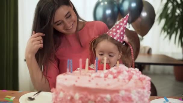 Mom and daughter are sitting at home at the table and celebrating their birthday. The girl is holding a red box in her hands. - Footage, Video