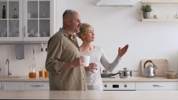 Volwassen paar drinken koffie praten op zoek naar kant In keuken Indoor - Video