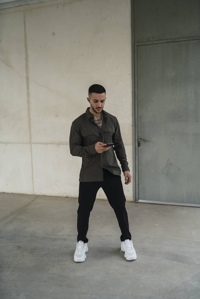 A Caucasian young man in casual style clothes holding a phone - Photo, Image