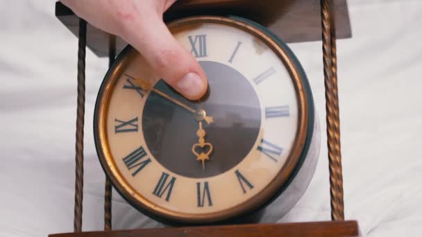 Mão masculina detém vintage clássico relógio de mesa de madeira com numerais romanos. Zoom - Filmagem, Vídeo