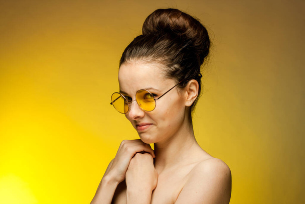 woman in yellow glasses naked shoulders gestures with hands - Photo, Image