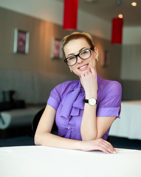 Happy young business woman sitting at the table in the room - 写真・画像