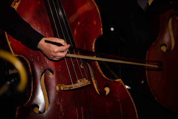Крупним планом рука грає на віолончелі
 - Фото, зображення