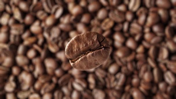 Super zpomalené makro záběr létající kávové zrno na pozadí čerstvě pražené kávy. - Záběry, video