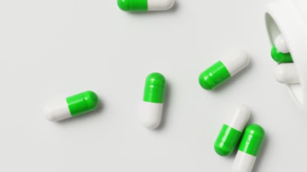 Wit-groene capsules vallen uit de fles op de tafel, bovenaanzicht, slow motion. Antivirale middelen, virusbescherming, Covid-19 behandeling. - Video
