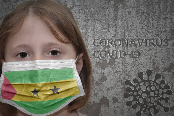Маленькая девочка в медицинской маске с флагом Сан-Томе и принципом стоит рядом со старой винтажной стеной с текстовым коронавирусом, ковидом и изображением вируса. Остановить вирус - Фото, изображение