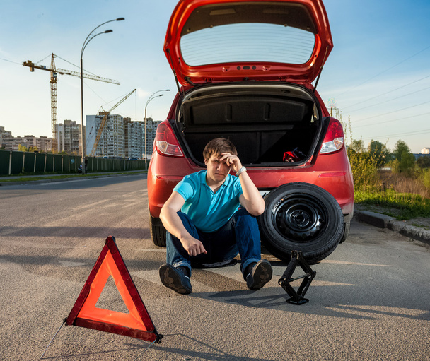 depressed man sitting near car with punctured tire - Fotografie, Obrázek