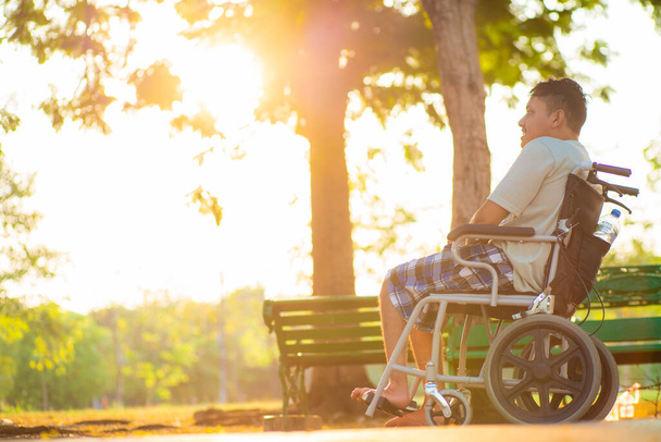 Homem incapacitado usando uma cadeira de rodas em um parque por do sol esperança conceito de vida - Foto, Imagem