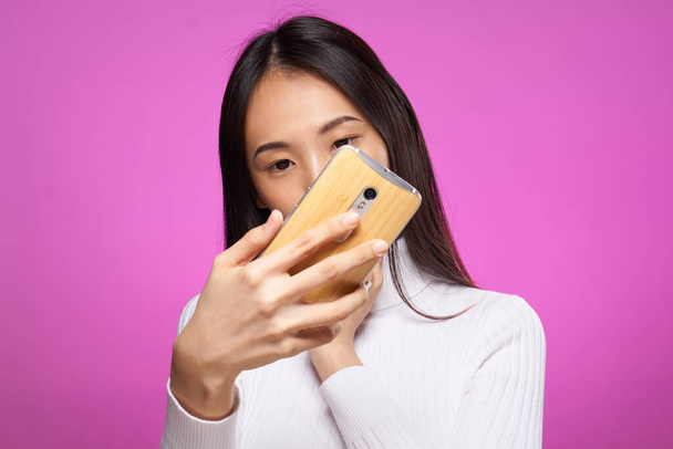 ázsiai nő nézi telefon internet technológia rózsaszín háttér - Fotó, kép