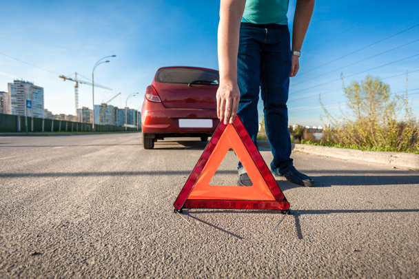 Человек ставит красный треугольник поет на дороге после автомобильной аварии
 - Фото, изображение