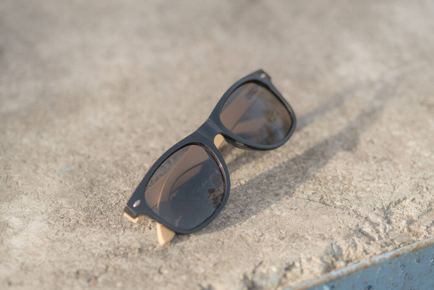 Modelo de gafas de sol clásicas con lentes negras disparar en lugar creativo al aire libre primer plano. Enfoque selectivo - Foto, Imagen